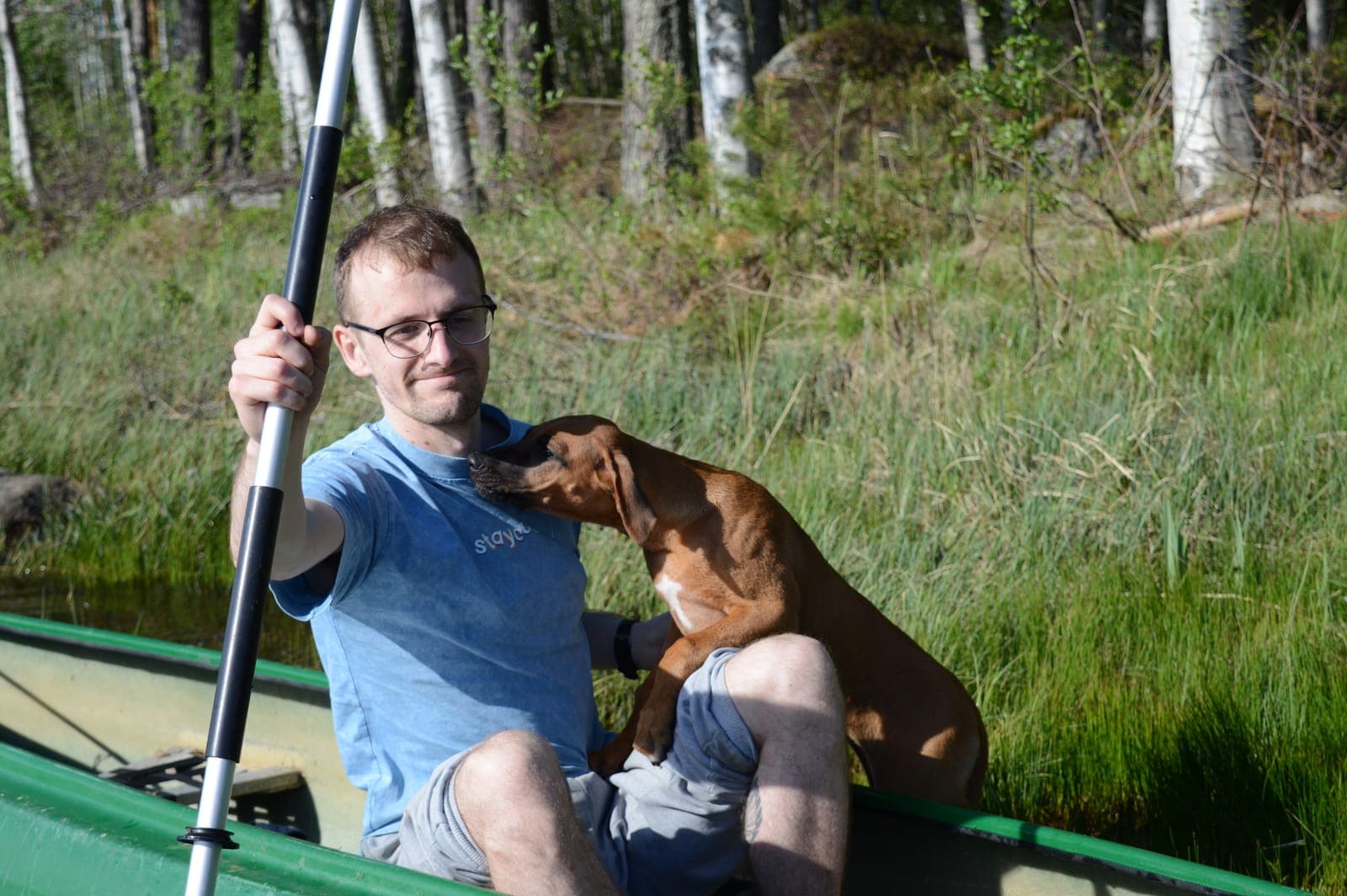 Curtis with his Rhodesian Ridgeback puppy Kirma in a canoe on a Finnish lake